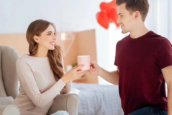 Agradecida chica sonriendo a novio trayendo su té — Foto de Stock