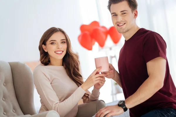 Pareja radiante sonriendo mientras se calienta con té aromático — Foto de Stock