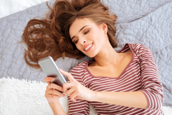 Chica feliz sonriendo mientras usa su teléfono inteligente — Foto de Stock