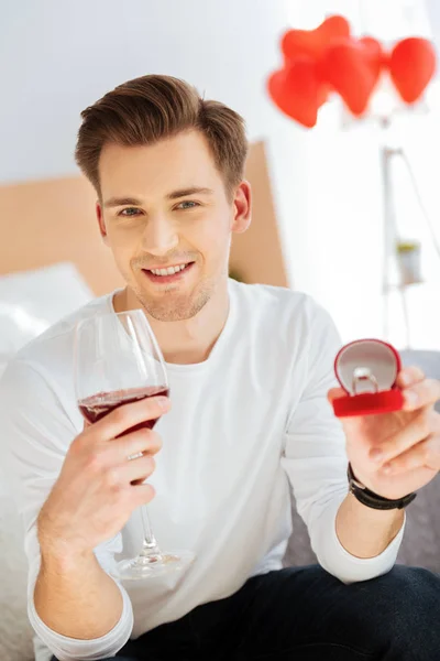 Happy young man holding engagement ring and drinking wine — Stock Photo, Image