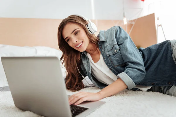 Весела дівчина посміхається під час роботи на ноутбуці — стокове фото