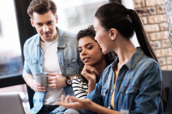 Wachsames Mädchen sitzt zwischen einem jungen Mann und einem anderen Mädchen — Stockfoto