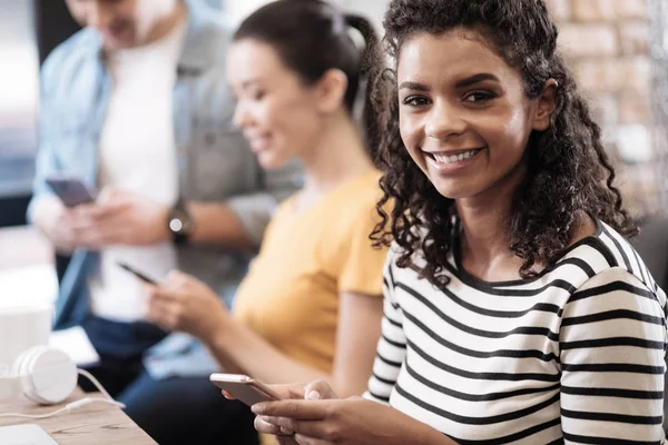 Lächelndes Mädchen sitzend und ihr Telefon haltend — Stockfoto