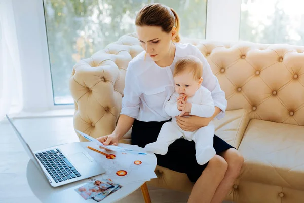 Serious businesswoman working at home while sitting with a baby — Stock Photo, Image