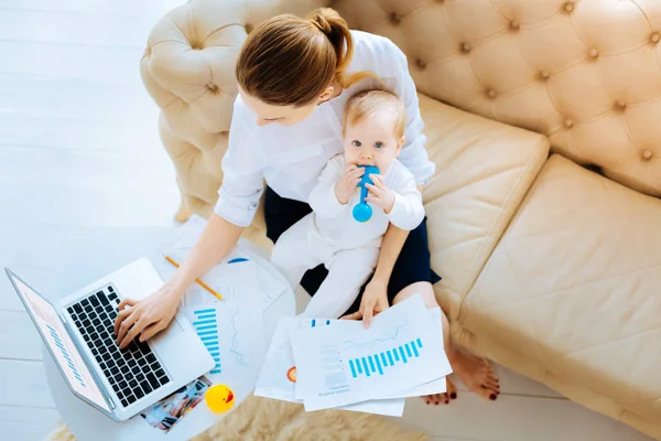 Busy businesswoman sitting with a funny baby — Stock Photo, Image