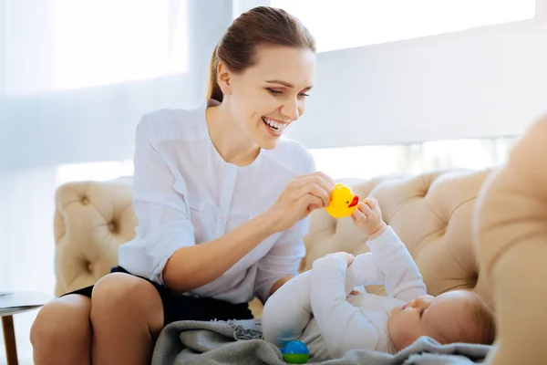 Felice giovane madre che dà un'anatra giocattolo a un bambino carino — Foto Stock