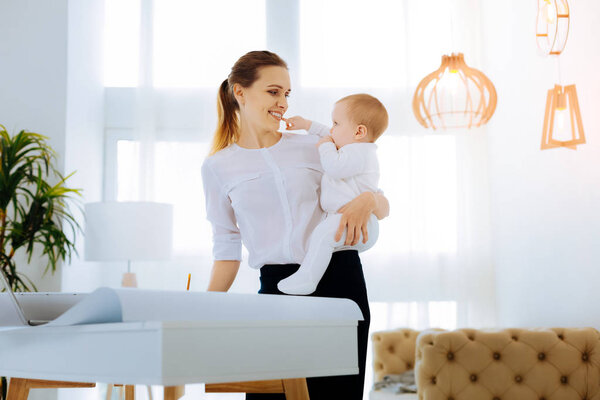 Милый малыш трогает зубы своей матери.
