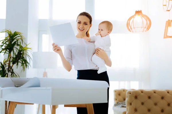 Glad arbetande mamma tittar på dokumentet — Stockfoto