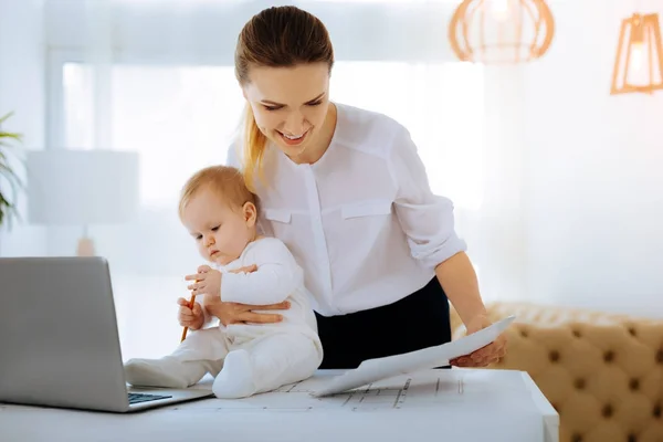 Mamma felice che fa un lavoro facile mentre è seduta con un bambino — Foto Stock