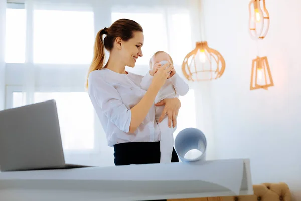 Kind young mother giving a bottle with water to her baby — Stock Photo, Image