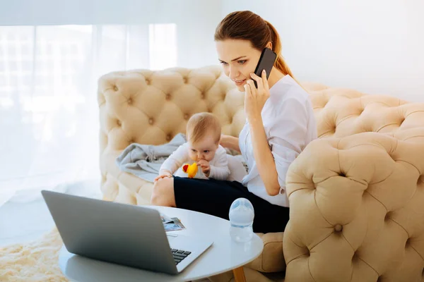 Занятая работающая мать разговаривает по телефону — стоковое фото