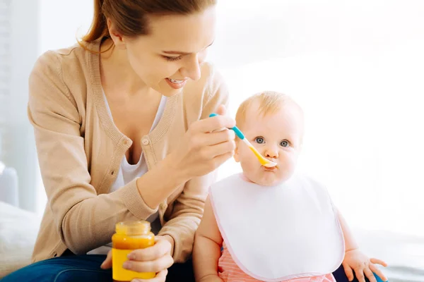 Agradável jovem mulher alimentando um bebê bonito — Fotografia de Stock