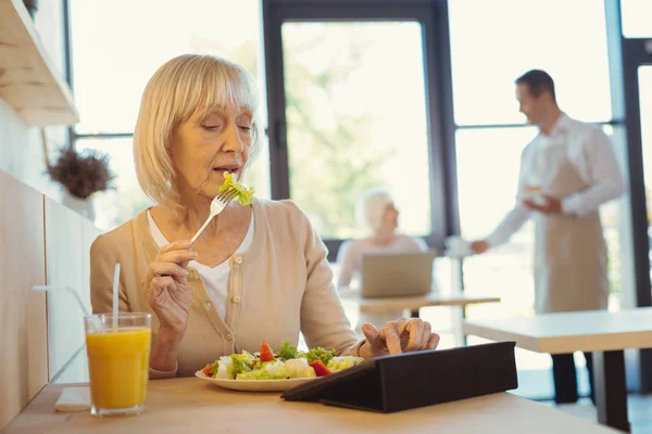 Mulher idosa agradável comer uma salada — Fotografia de Stock