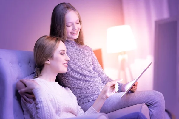 Sonrientes mamá y niña sentadas juntas y abrazadas —  Fotos de Stock