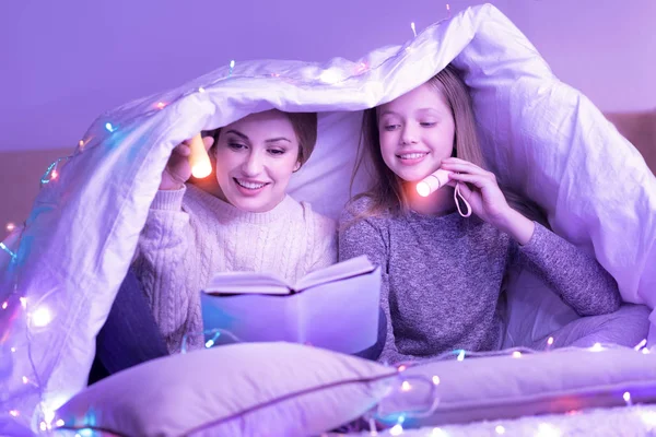 Hingebungsvolle Mutter und Tochter lesen unter der Decke — Stockfoto