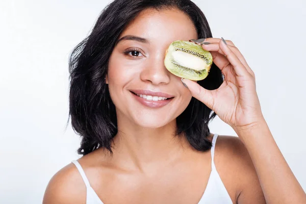 Mulher segurando kiwis perto de seu olho — Fotografia de Stock