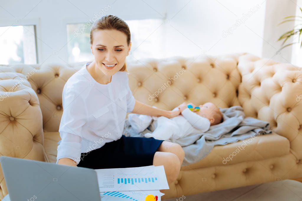 Cheerful businesswoman taking care of her baby
