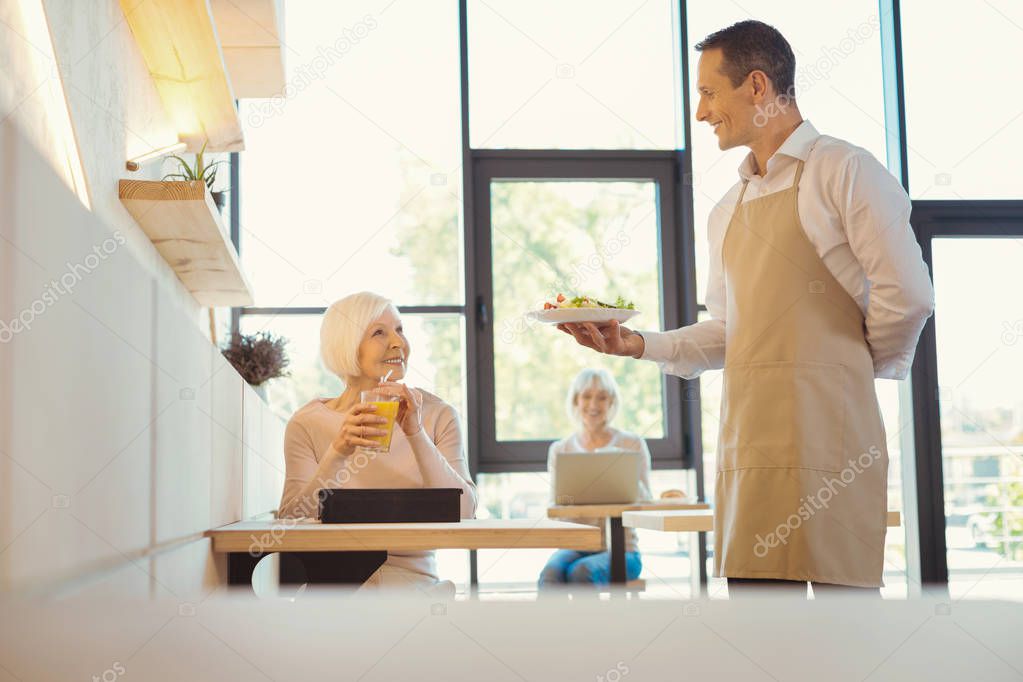 Positive elderly woman looking at the waiter