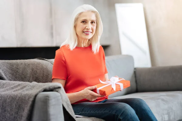 Joyful äldre kvinna som håller en present — Stockfoto
