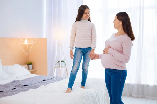 Utmärkt gravid kvinna som håller sin dotter i handen — Stockfoto