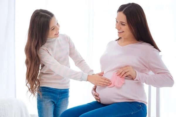 Chica atractiva positiva que lleva sobre el bebé en la panza de las mamás — Foto de Stock