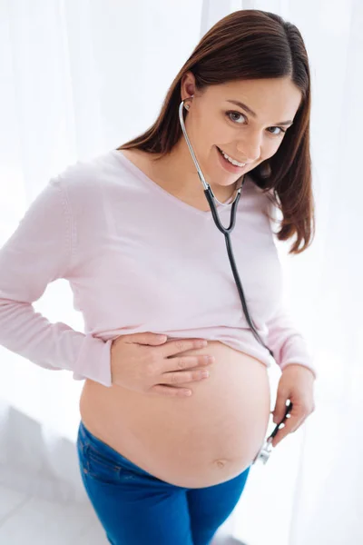 Enthousiaste femme enceinte examinant son ventre — Photo