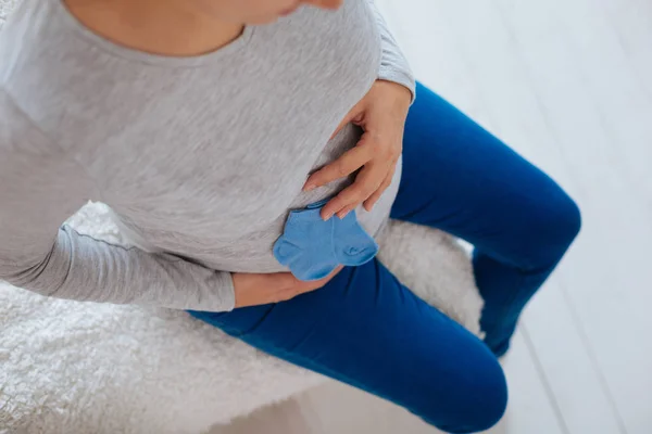 Hamile kadını karnından küçük mavi çorap koymak — Stok fotoğraf