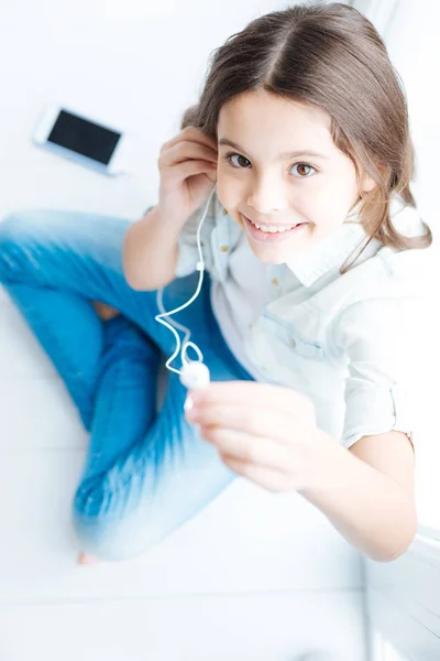 Brunette happy girl gives earphone — Stock Photo, Image