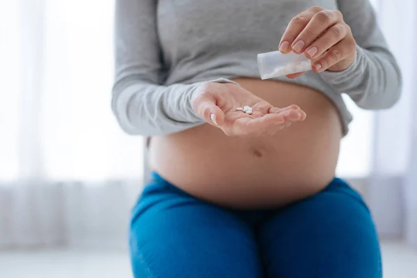 Беременная спокойная женщина держит в руках витамины — стоковое фото