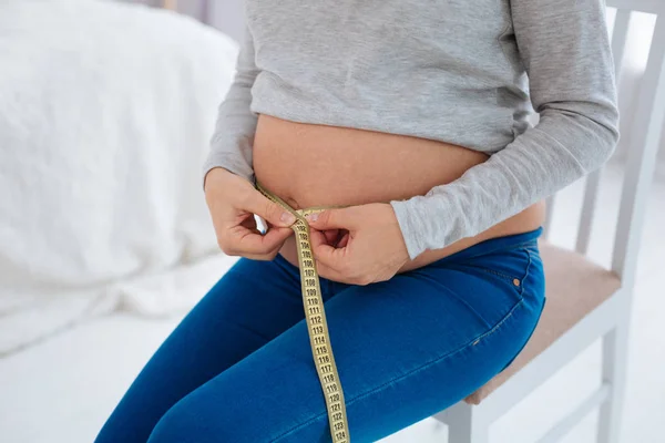 Беременная женщина руки измерения ее талии — стоковое фото