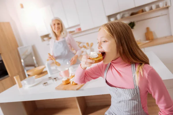 Радісна приємна дівчина кусає булочку — стокове фото