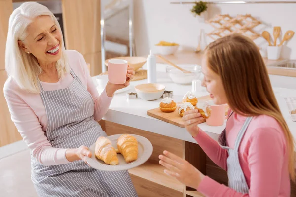 Mulher idosa feliz oferecendo croissants — Fotografia de Stock