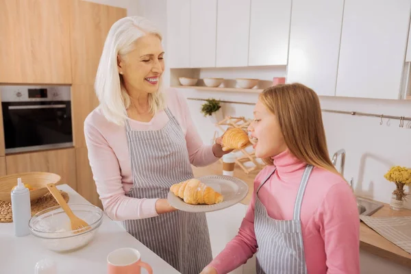 Nöjd äldre kvinna som håller en croissant — Stockfoto