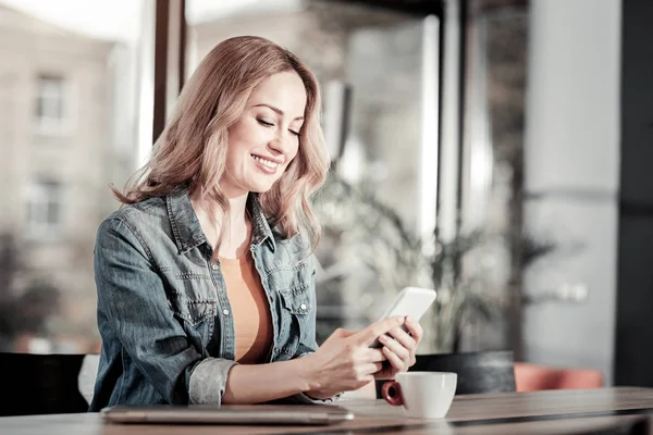 Feliz mujer sonriente sentada en un café y leyendo mensajes —  Fotos de Stock