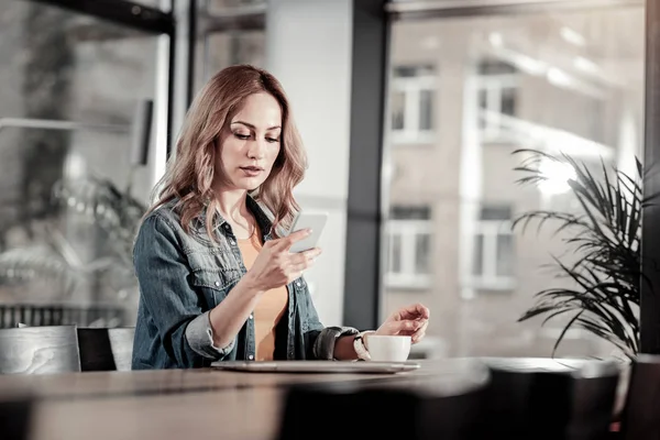 Uppmärksamma koncentrerad kvinna som tittar på din smartphone — Stockfoto