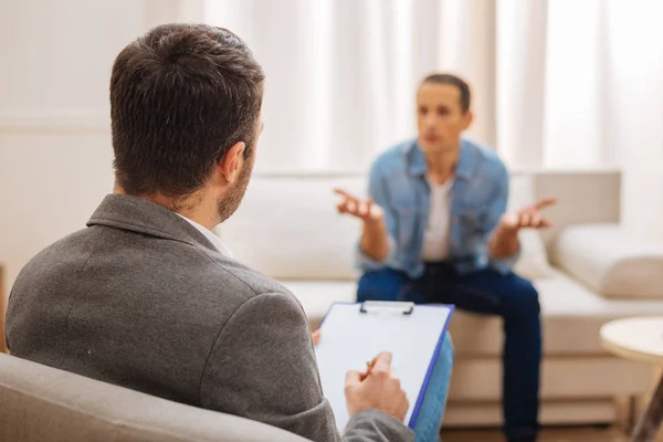 Männlicher ernsthafter Psychologe hört seinem Patienten zu — Stockfoto