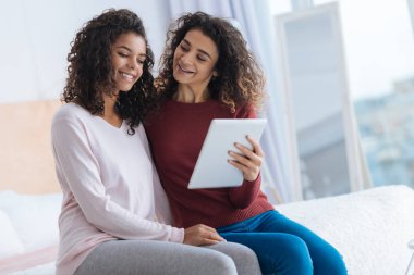 Touchpad tutarak ve kızkardeşi ile gülümseyen meraklı genç kadın