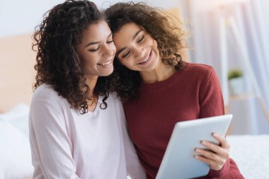 Tablet bilgisayarda bakarken sarılma sevgi dolu kadın kardeşler