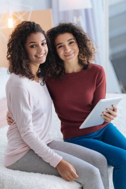 Kameraya bakarak ve evde gülümseyen genç ve güzel bayanlar