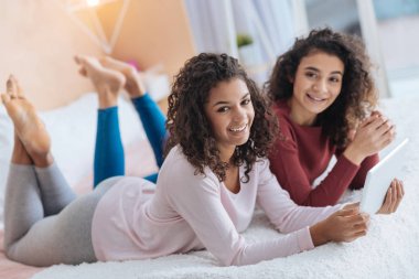 Güler kardeşler yatakta yatarken ise tablet bilgisayar kullanarak