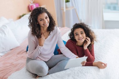 Kameraya gülümseyen touchpad ile neşeli kıvırcık saçlı kardeşler