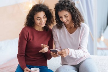 Genç bayanlar bir şey smartphone üzerinde tartışırken gülümseyen