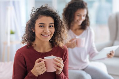 Çekici kız fincan sıcak çay tam tutarken gülümseyen