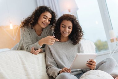 Gülümseyen kız kardeş bir şey dijital tablet üzerinde tartışıyor