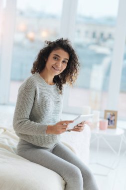 Yatağın üstüne oturan ve touchpad kullanarak dost görünümlü genç bayan