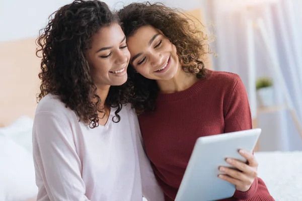 Kärleksfull kvinnliga syskon kramar medan du tittar på tablet PC — Stockfoto