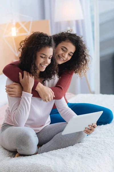 Φιλικό νεαρές κυρίες που αγκαλιάζει ενώ κοιτάζοντας τον υπολογιστή tablet — Φωτογραφία Αρχείου