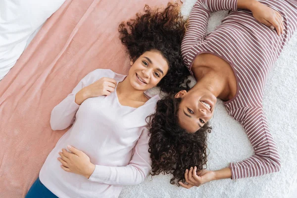 Radosny kobiece rodzeństwo w casual leżąc na łóżku — Zdjęcie stockowe