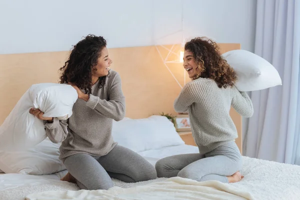 Irmãos extremamente felizes lutando com travesseiros em casa — Fotografia de Stock