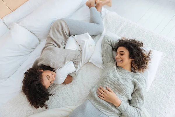 Belles filles embauchées bouclés bavarder sur le lit et sourire — Photo